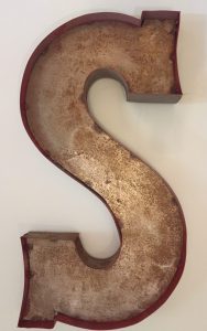 large letter S made of rusty metal